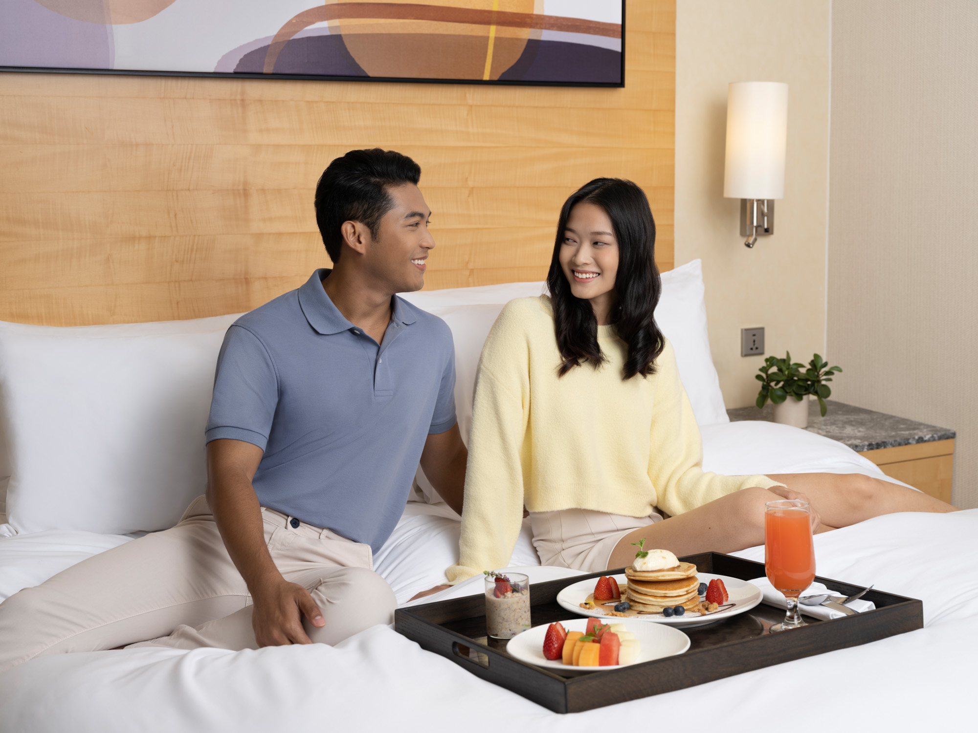 commercial lifestyle photoshoot of young couple having breakfast in bed at voco hotel singapore