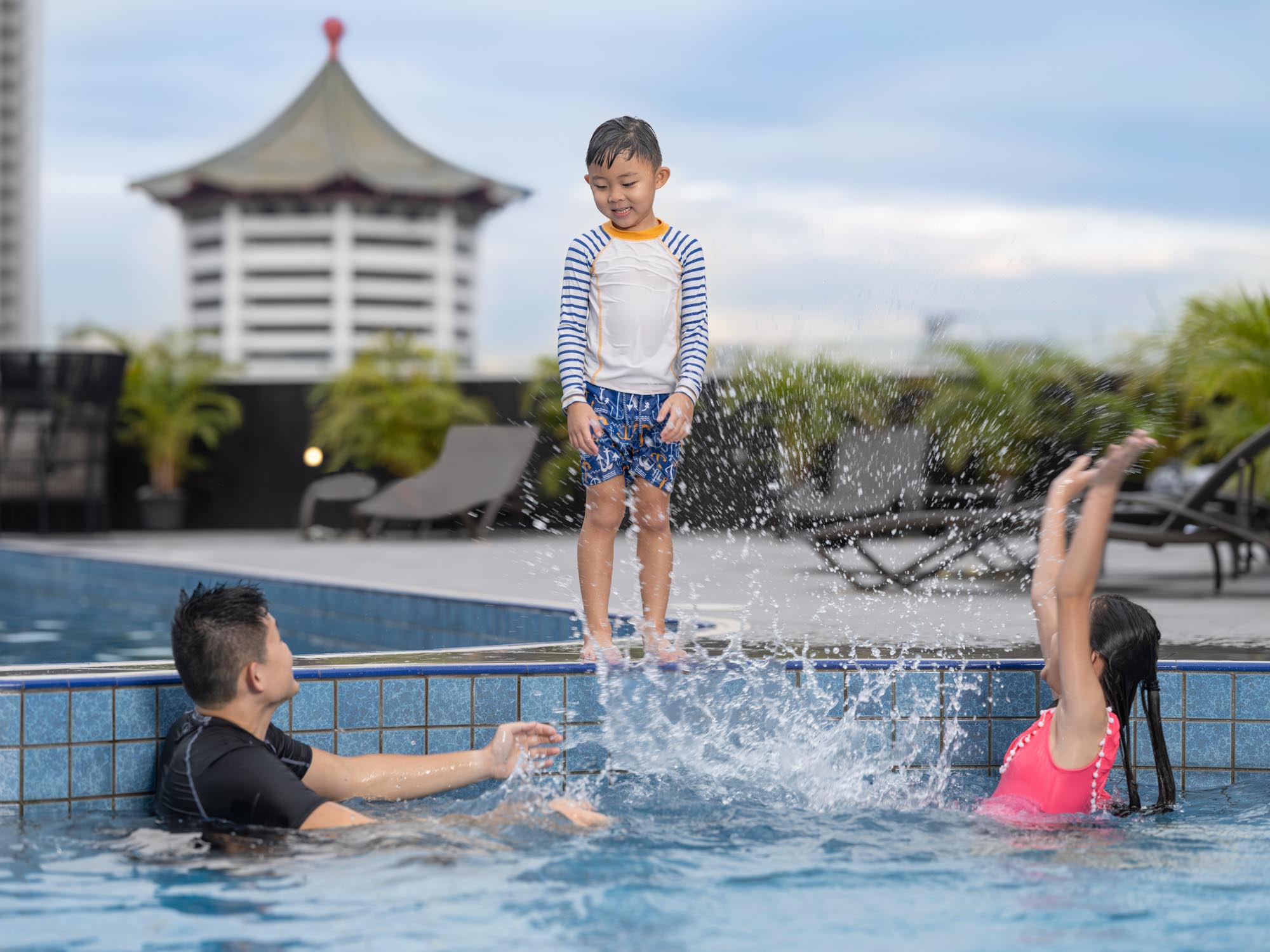 commercial lifestyle photo of young family playing in pool at voco hotel singapore