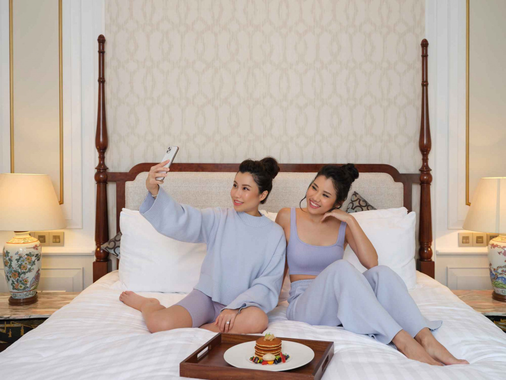 2 ladies taking a selfie in bed with a plate of pancakes in Intercontental Hotel photo