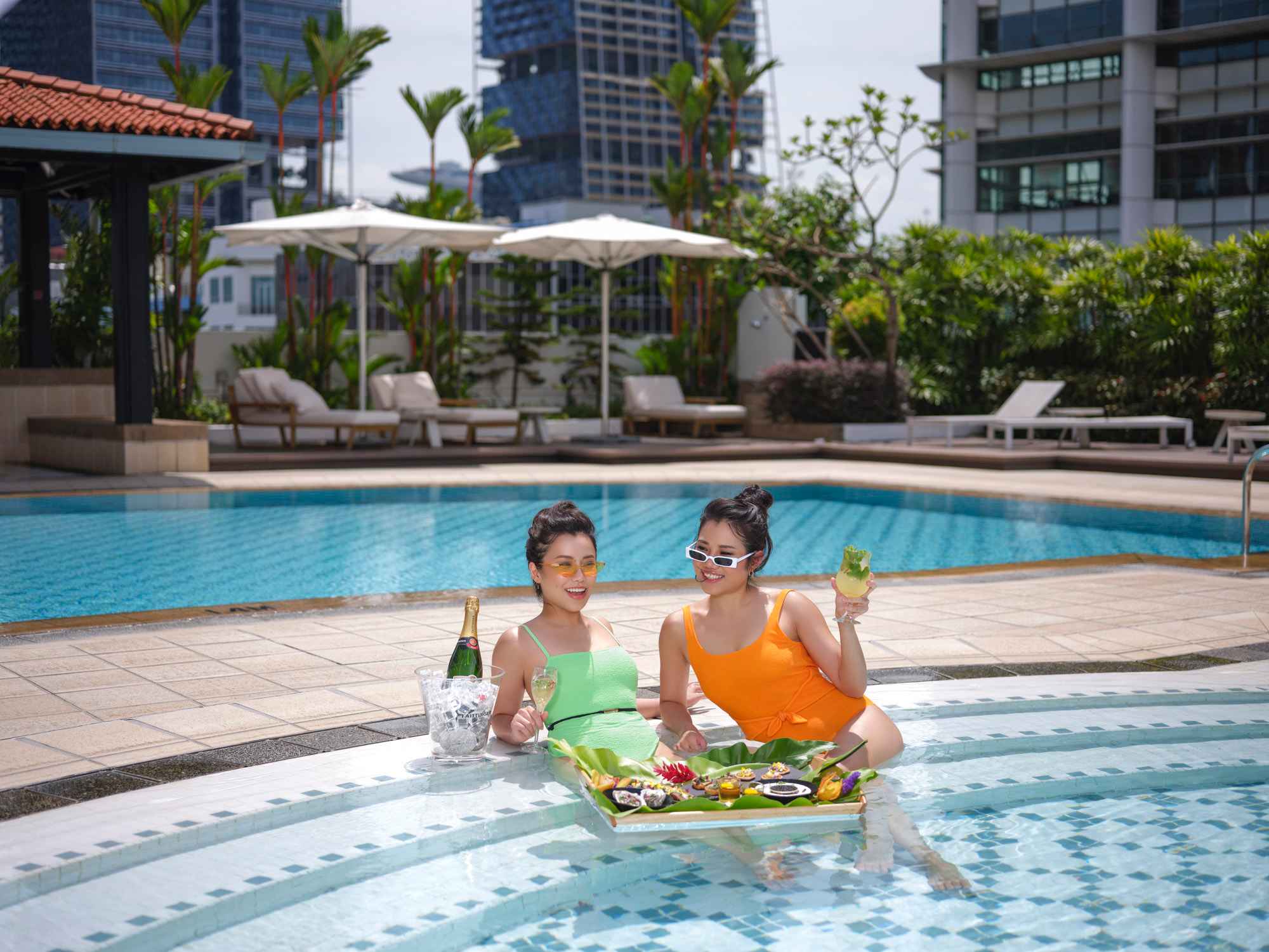 2 ladies chilling at the swimming pool at intercontinental hotel with drinks and food - hotel photography