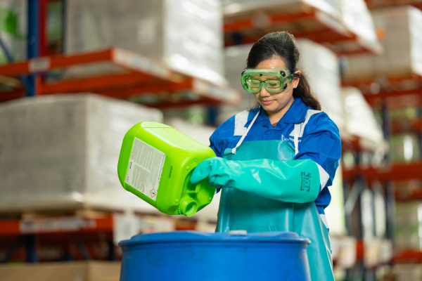 Wihelmson Industrial Photography - lady in protective gear pouring liquid into tanks