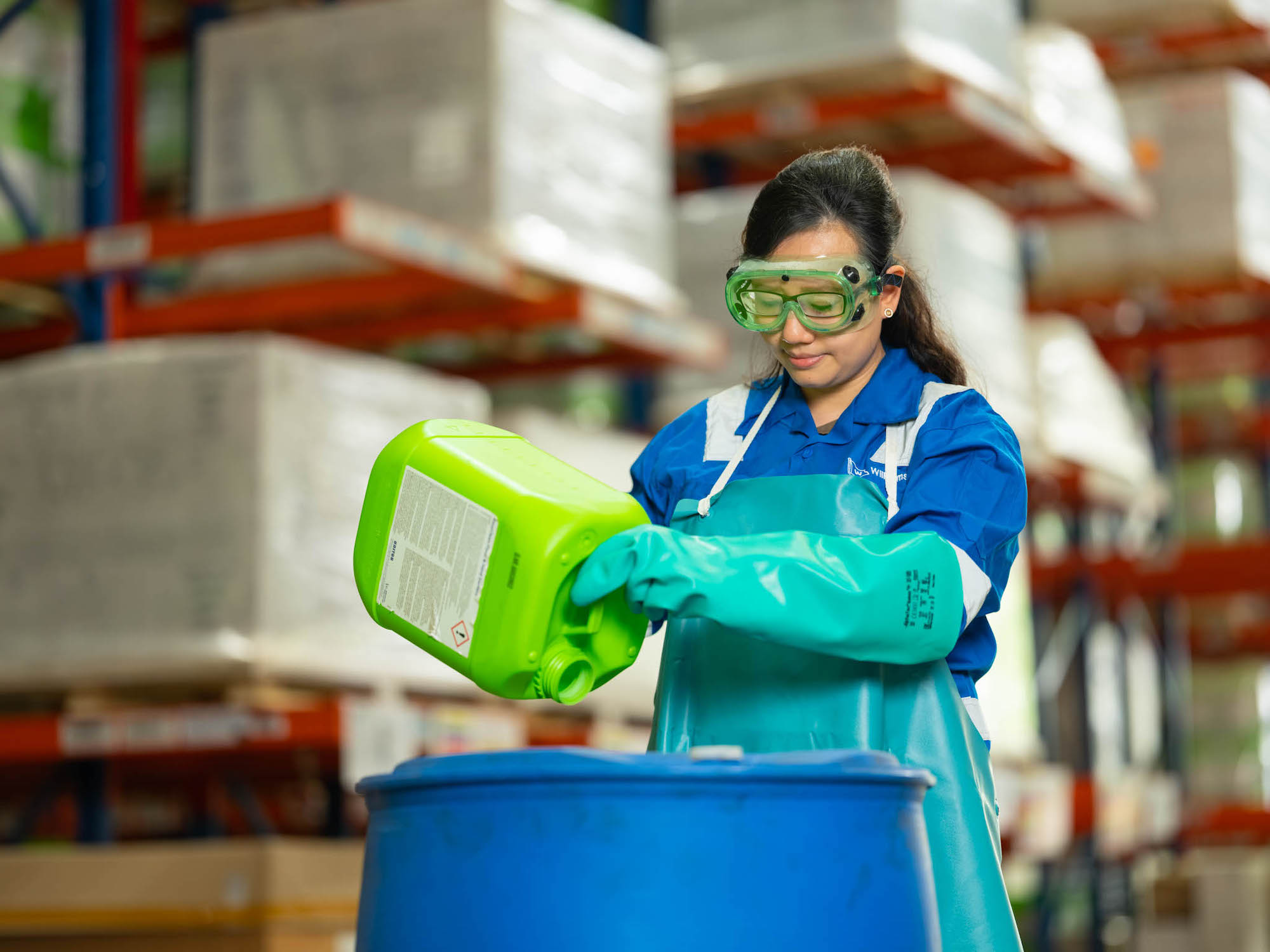 Wihelmson Industrial Photography - lady in protective gear pouring liquid into tanks