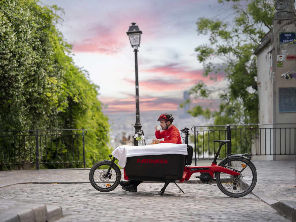 Livreur Parnass prend son petit-déjeuner sur son vélo cargo à Montmartre