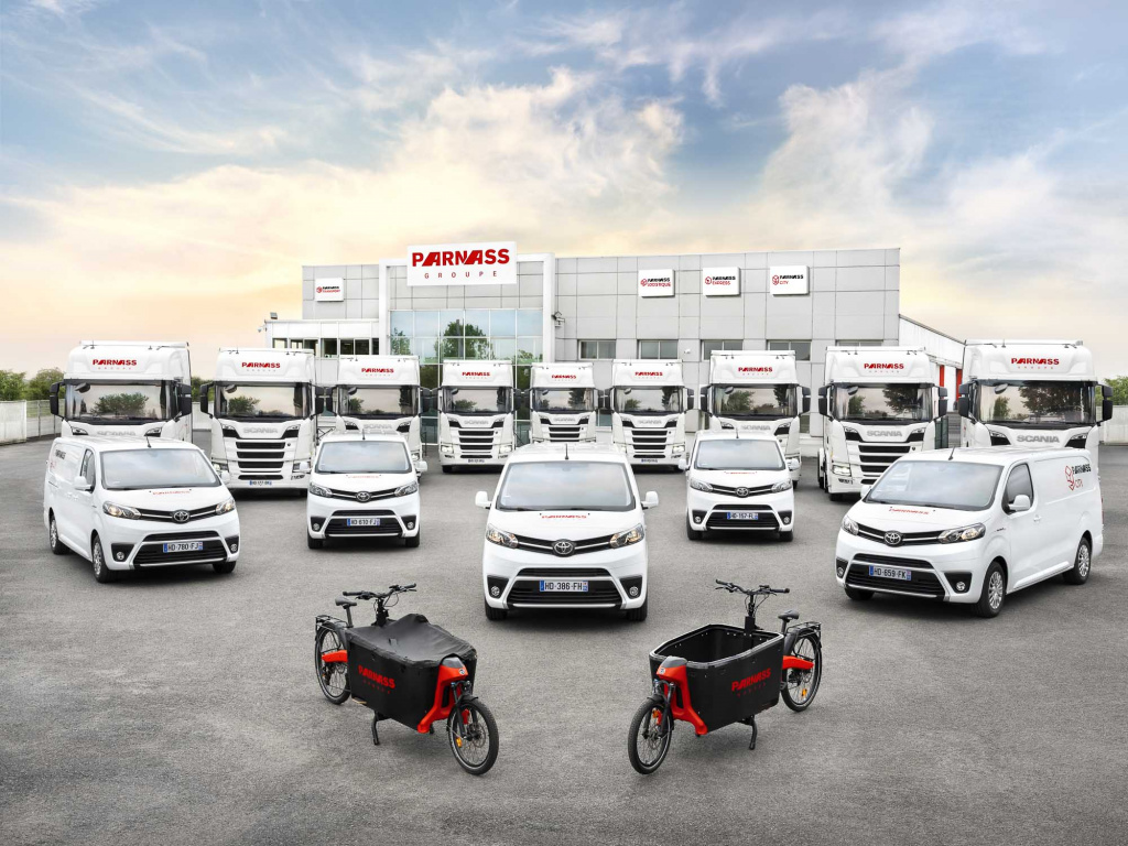 Camions, utilitaires et vélos cargos Parnass Transport devant un bâtiment du groupe